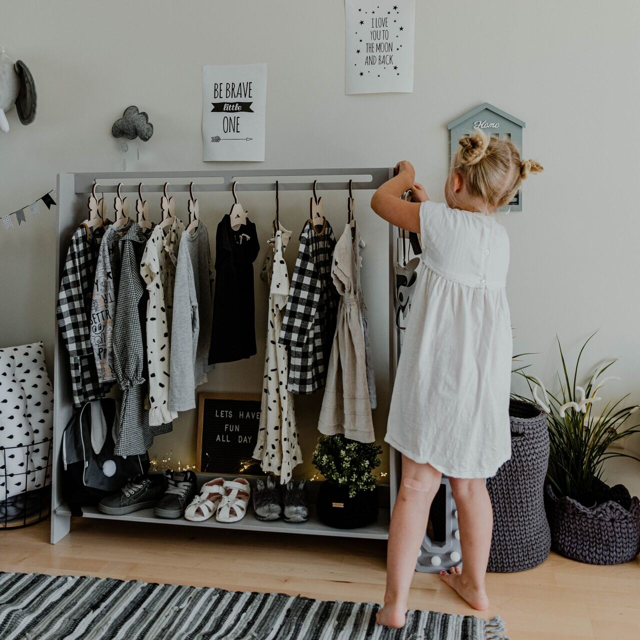 A little girl picking her own clothes from a Montessori rack